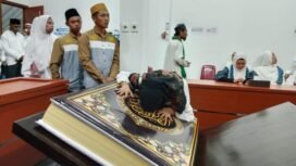 Seorang umat muslim terlihat sedang mencium Al Qur'an raksasa sebagai ungkapan syukur. Foto: Istimewa