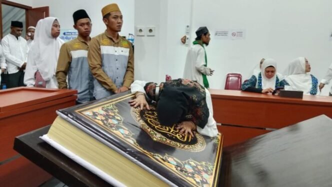 
Seorang umat muslim terlihat sedang mencium Al Qur'an raksasa sebagai ungkapan syukur. Foto: Istimewa