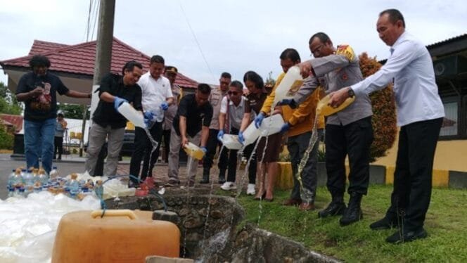 
Kapolres Mimika bersama tamu undangan saat memusnahkan miras lokal jenis sopi dengan cara dituangkan ke dalam parit. (Foto: TIM Sasagupapua.com)