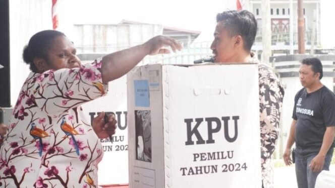 
Delima Murib saat mengisi surat suara ke dalam kotak. (Foto: Kristin Rejang)