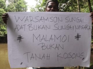 Seorang pemuda dari Masyarakat Adat Moi saat memegang seruan penolakan pembangunan bendungan Warsamson. (Foto: Istimewa)