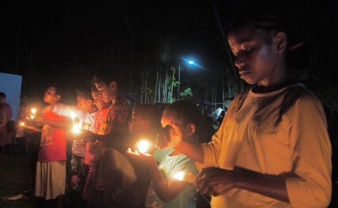 
Anak-anak saat menyalakan lilin usai Nobar Pesta Babi. (Foto: Kristin Rejang/Sasagupapua.com) 