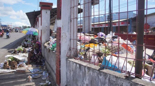 Tampak mama-mama Papua sedang berjualan di pinggir jalan depan Pasar Karang,  namun dibagian belakang tumpukan sampah yang menggunung di dalam area Pasar. (Foto: Kristin Rejang/Sasagupapua.com) 