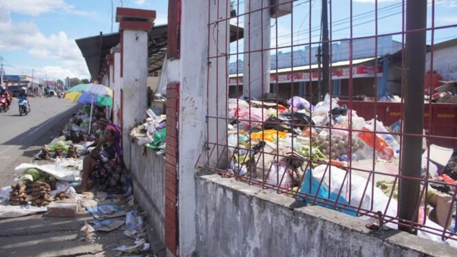 
Tampak mama-mama Papua sedang berjualan di pinggir jalan depan Pasar Karang,  namun dibagian belakang tumpukan sampah yang menggunung di dalam area Pasar. (Foto: Kristin Rejang/Sasagupapua.com) 