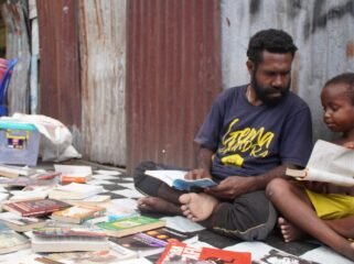 Pegiat Literasi, Mecky Tebai saat berbincang dengan seorang anak saat menggelar lapak baca di komplek Mapiduba. (Foto: Kristin Rejang/Sasagupapua)