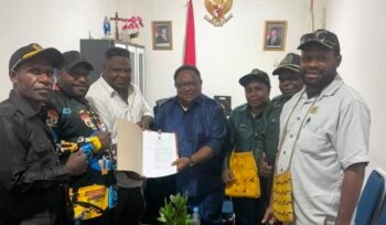 Wakil Ketua IV DPR Papua Tengah, John Gobai saat menyerahkan salinan Perdasi terkait pertambangan rakyat. (Foto: Ist)