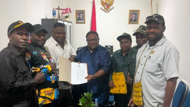 
Wakil Ketua IV DPR Papua Tengah, John Gobai saat menyerahkan salinan Perdasi terkait pertambangan rakyat. (Foto: Ist)