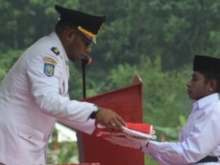 Kepala Distrik Mimika Barat Jauh, Ever Kukuareyau saat menyerahkan bendera kepada pembawa baki Paskibra dalam momen upacara HUT ke-81 RI, Jumat (17/8/2026). Foto: Dok DMBJ. 