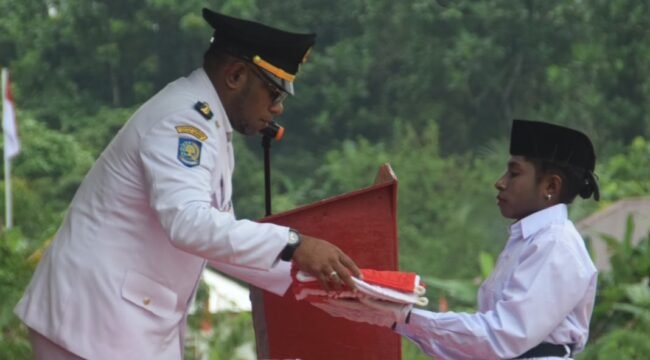 Kepala Distrik Mimika Barat Jauh, Ever Kukuareyau saat menyerahkan bendera kepada pembawa baki Paskibra dalam momen upacara HUT ke-81 RI, Jumat (17/8/2026). Foto: Dok DMBJ. 